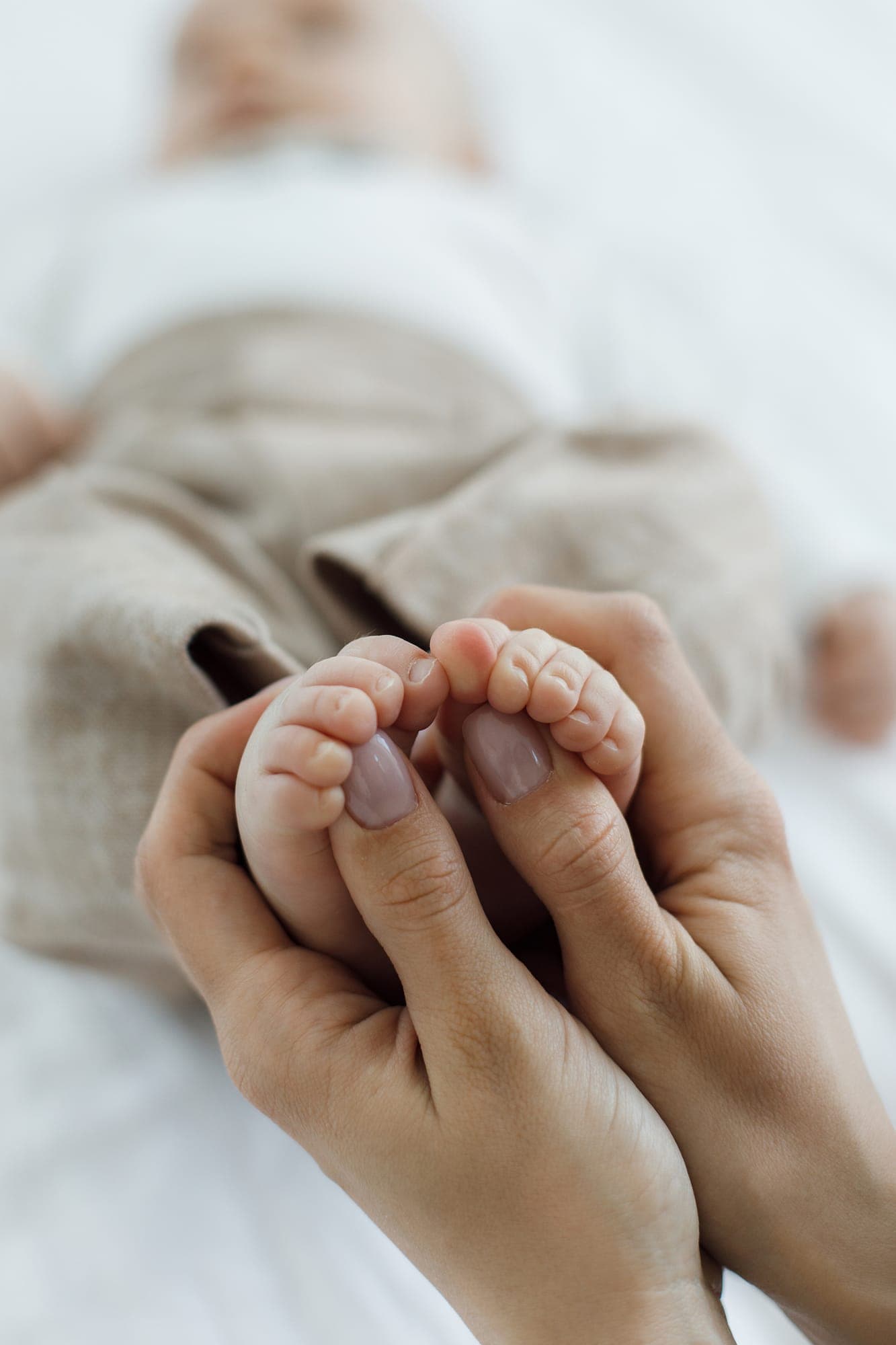 Atelier massage bébé à domicile Mains d’adulte massant les pieds d’un bébé pendant un atelier massage bébé
